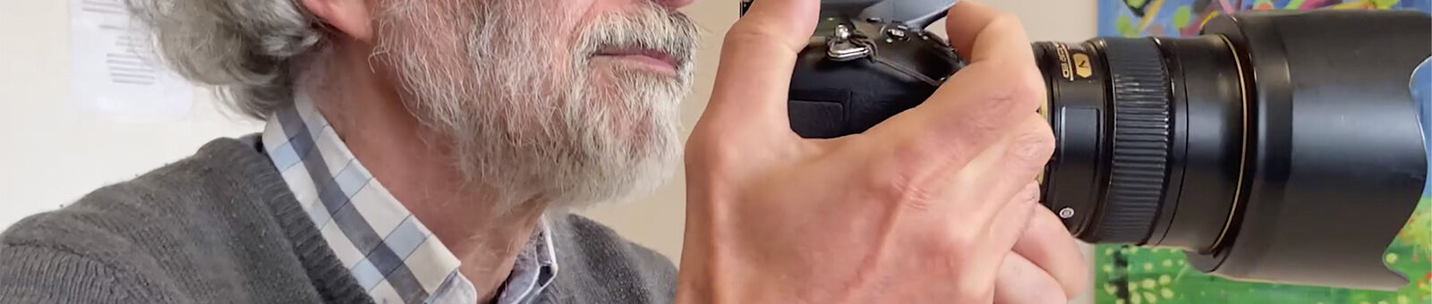 Un homme aux cheveux gris regarde un appareil photo