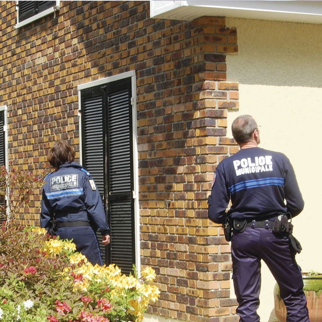 2 agents de la police municipale vérifient une maison.