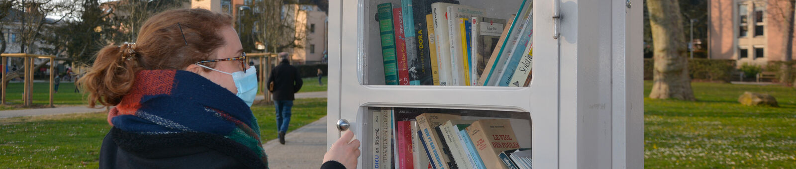 Une femme consulte les ouvrages dans la boîte à livres du centre-ville