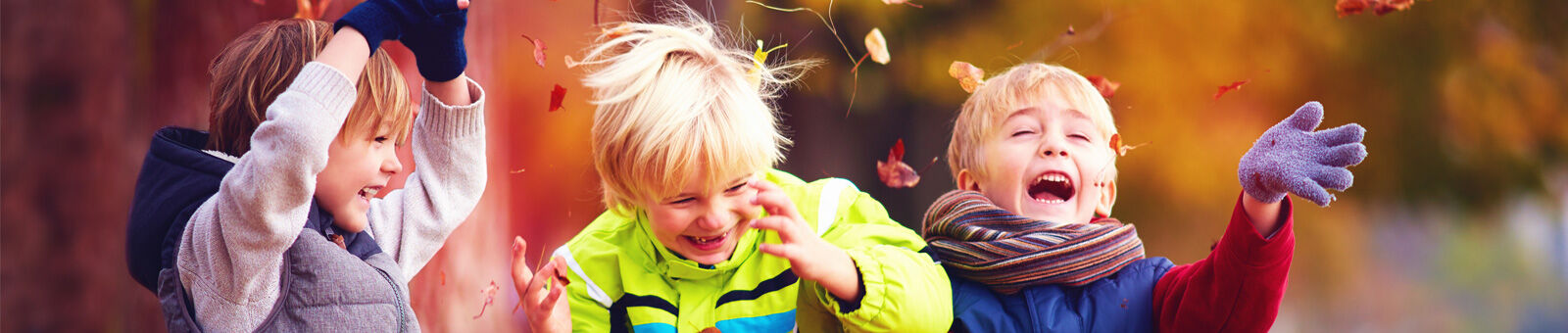 3 petits garçons jouent avec les feuilles mortes