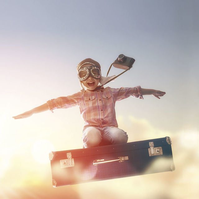 Enfant dans les airs sur une valise.