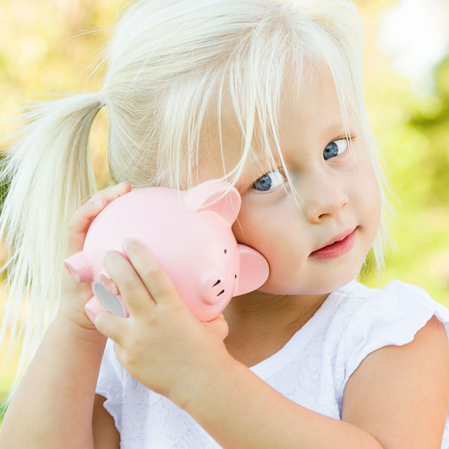 Jeune enfant avec une tirelire dans la main.