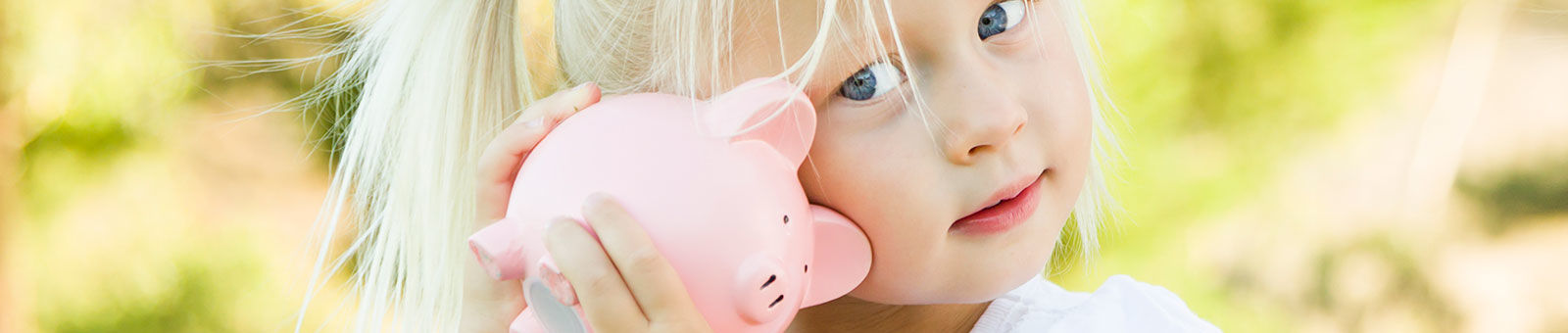 Jeune enfant avec une tirelire dans la main.